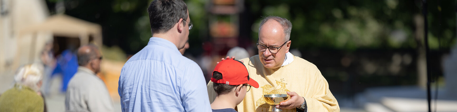 Stiftspfarrer teilt eine Hostie an Gläubige aus 