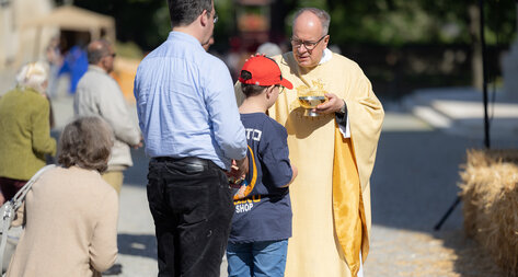 Stiftspfarrer teilt eine Hostie an Gläubige aus 
