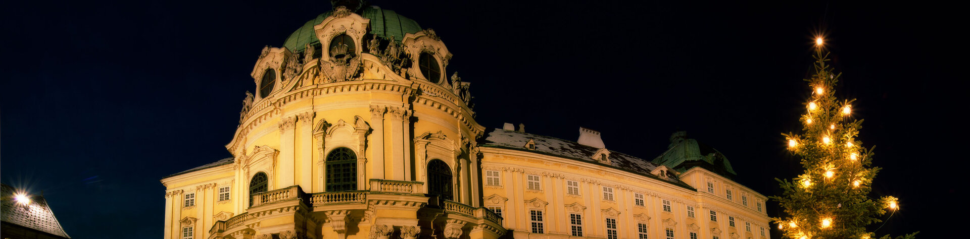 Das hell beleuchtete Stift in der Nacht, rechts ein beleuchteter Christbaum im Schnee
