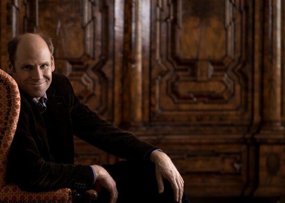 Der Musiker Christoph Ehrenfellner blickt lächeln in die Kamera.