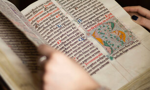 Hände blättern in einer mittelelterlichen Handschrift