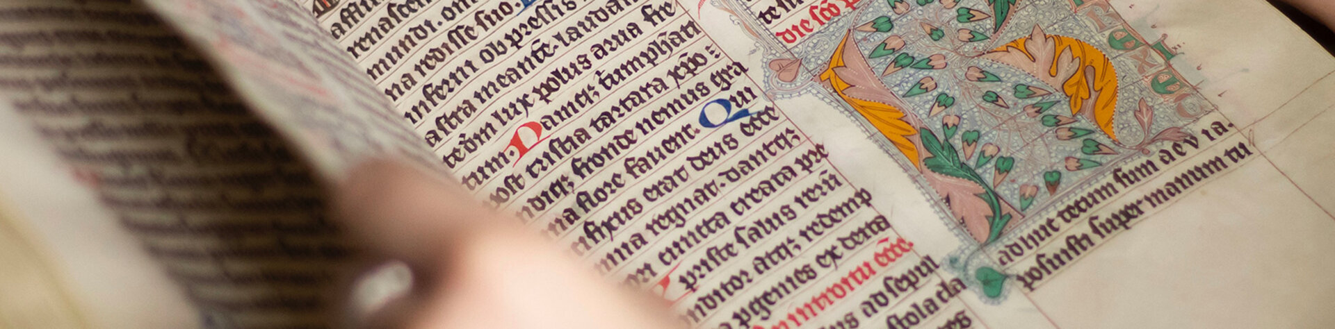 Hände blättern in einer mittelelterlichen Handschrift