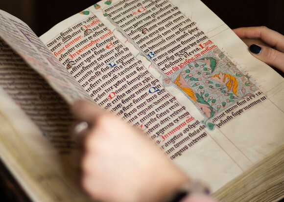 Hände blättern in einer mittelelterlichen Handschrift