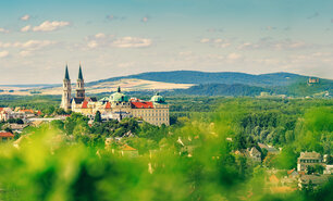 Blick auf das Stift Klosterneuburg umgeben von grüner Landschaft und Hügeln.