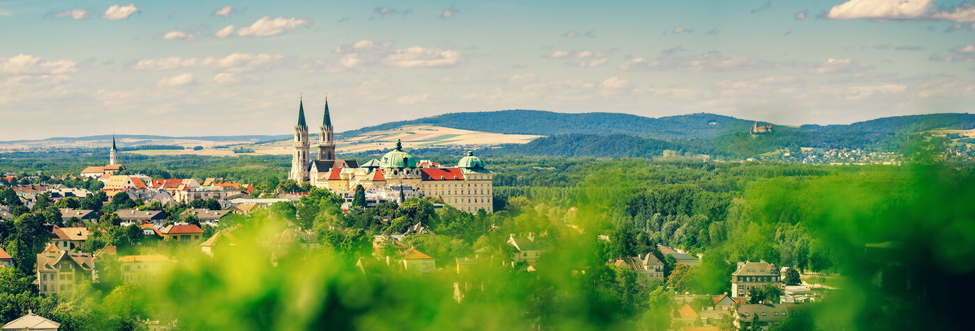 Blick auf das Stift Klosterneuburg umgeben von grüner Landschaft und Hügeln.