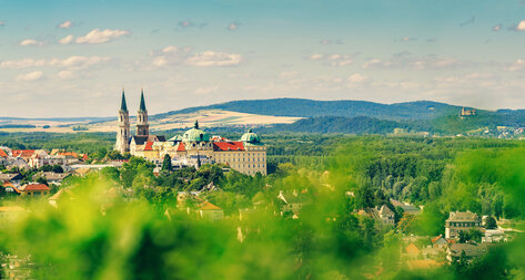 Blick auf das Stift Klosterneuburg umgeben von grüner Landschaft und Hügeln.