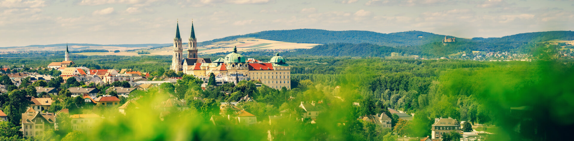 Blick auf das Stift Klosterneuburg umgeben von grüner Landschaft und Hügeln.