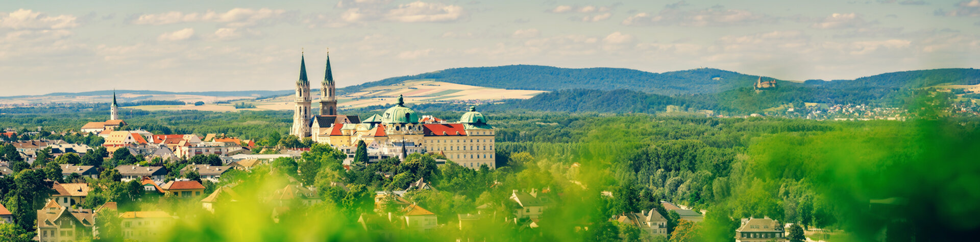 Blick auf das Stift Klosterneuburg umgeben von grüner Landschaft und Hügeln.