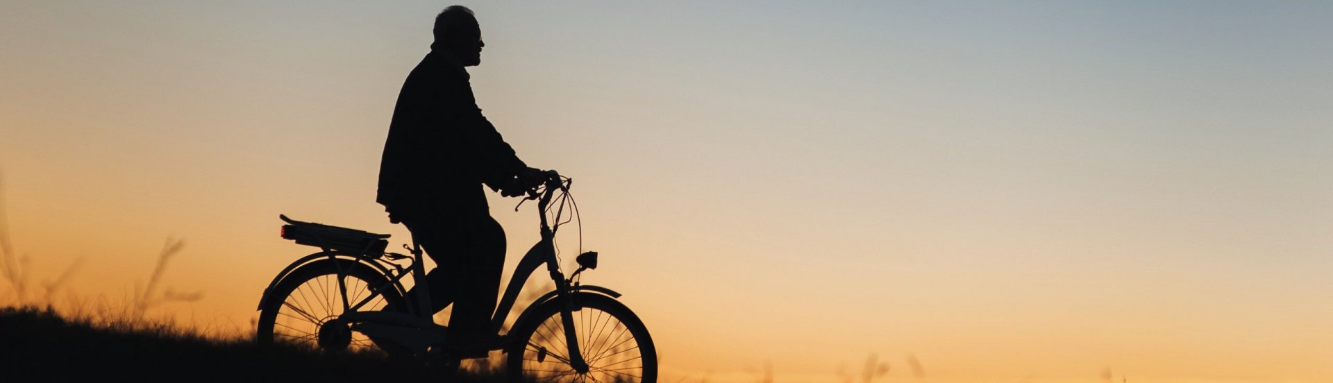 Silhouette eines Mannes, der mit dem Fahrrad einen Berg hinunterfährt